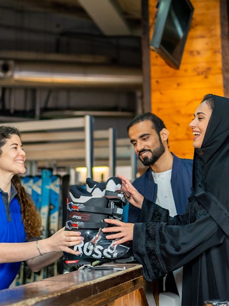 Ski Dubai visitors receiving ski boots from staff at Snow Park entrance.