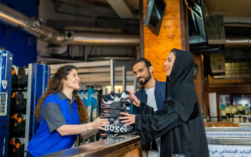 Ski Dubai visitors receiving ski boots from staff at Snow Park entrance.