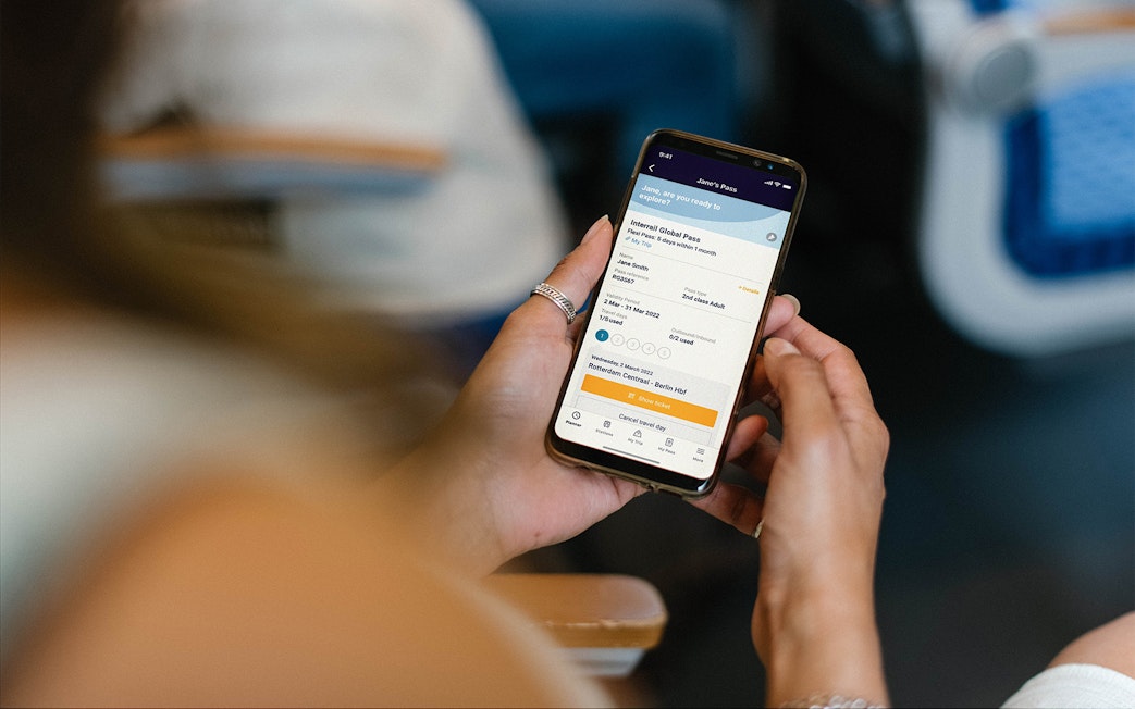 Person holding phone displaying Interrail Global Mobile Pass Flex booking.