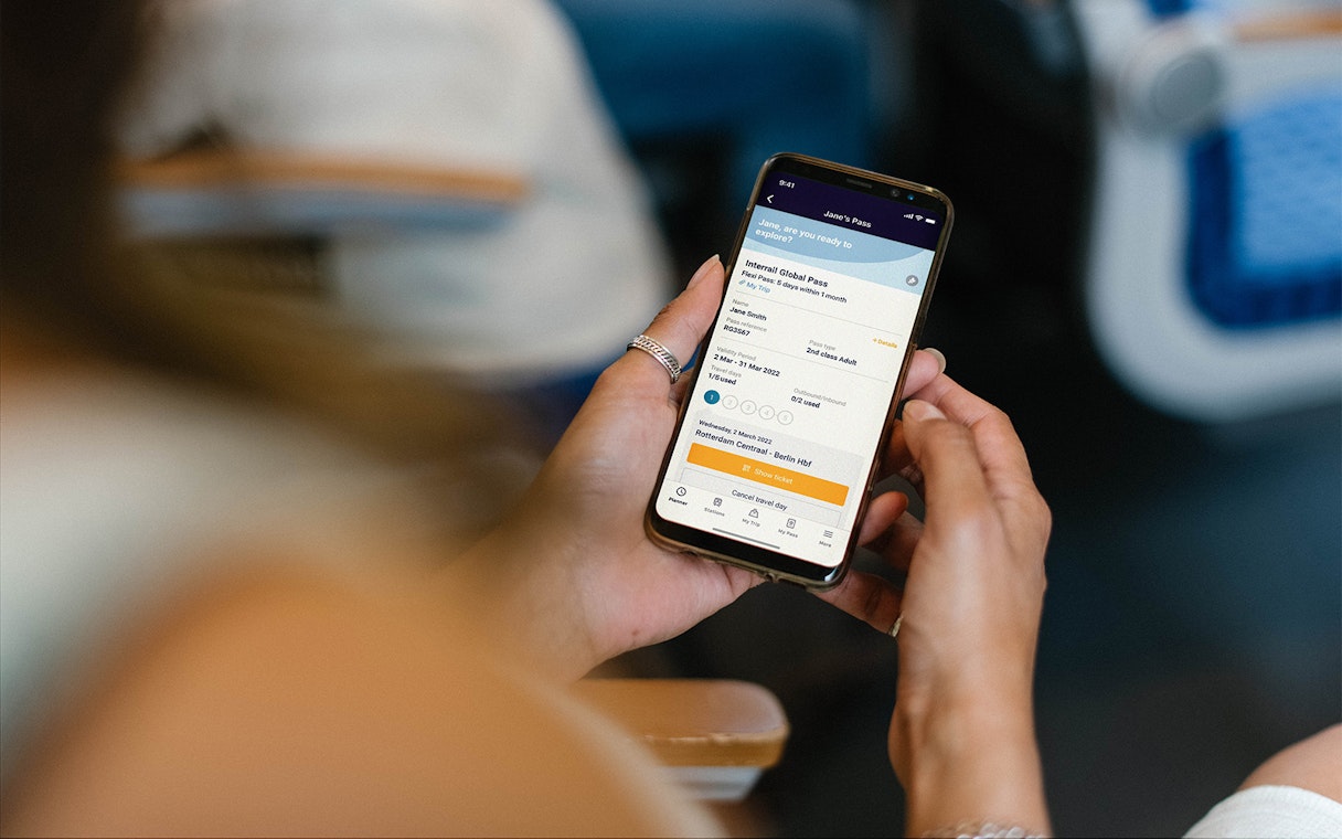 Person holding phone displaying Interrail Global Mobile Pass Flex booking.