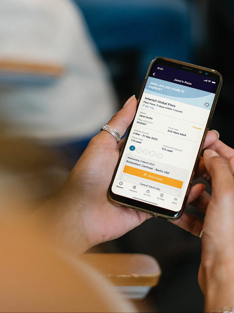 Person holding phone displaying Interrail Global Mobile Pass Flex booking.