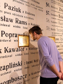 Man examining exhibit wall at Oskar Schindler's Factory museum in Krakow, Poland.