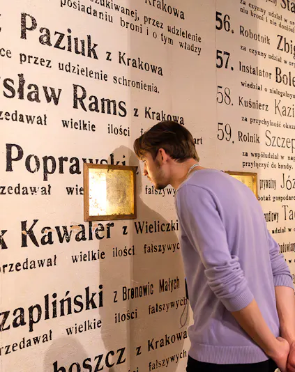 Man examining exhibit wall at Oskar Schindler's Factory museum in Krakow, Poland.