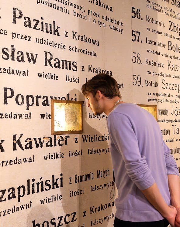 Man examining exhibit wall at Oskar Schindler's Factory museum in Krakow, Poland.