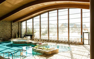 Indoor pool area at Terma Bania in Białka Tatrzańska with large windows and lounge chairs.