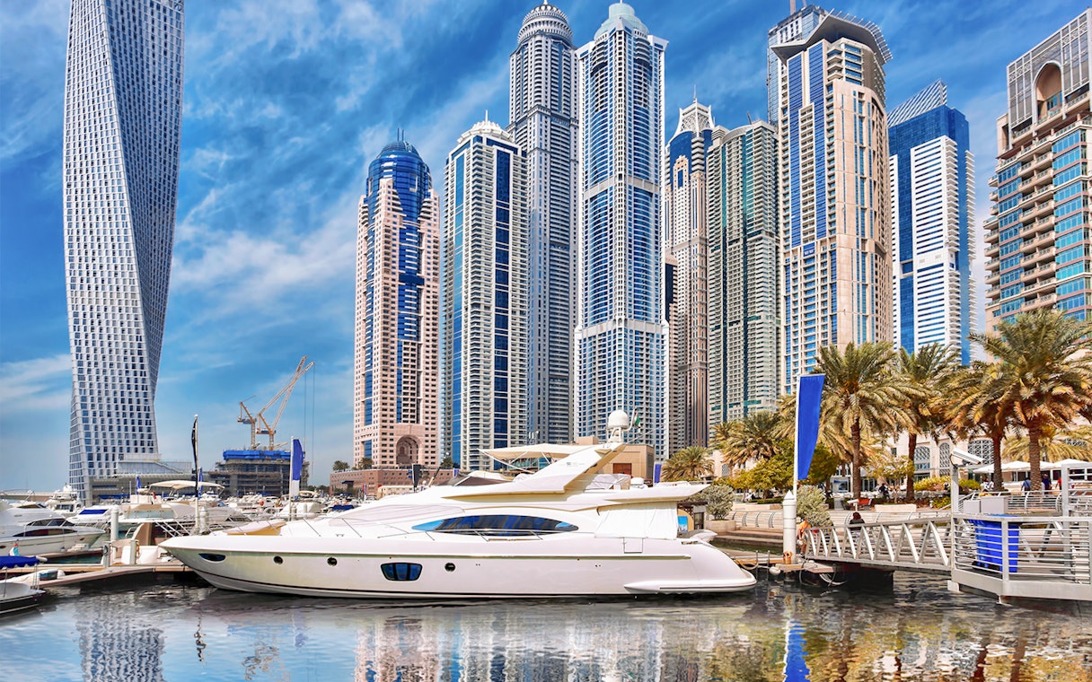 Yacht docked in Dubai Marina with skyscrapers in the background.
