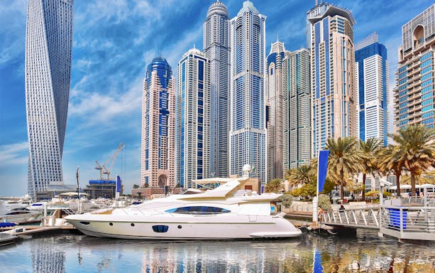 Yacht docked in Dubai Marina with skyscrapers in the background.