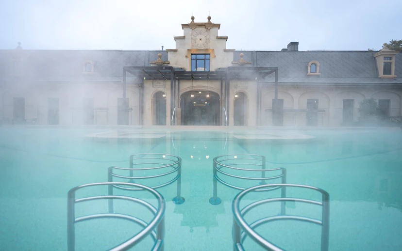 Milan spa with steaming hot pool and historic building in daylight.