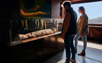 Visitors viewing a mummy exhibit during the Mount Teide Tour with Cable Car Ride.