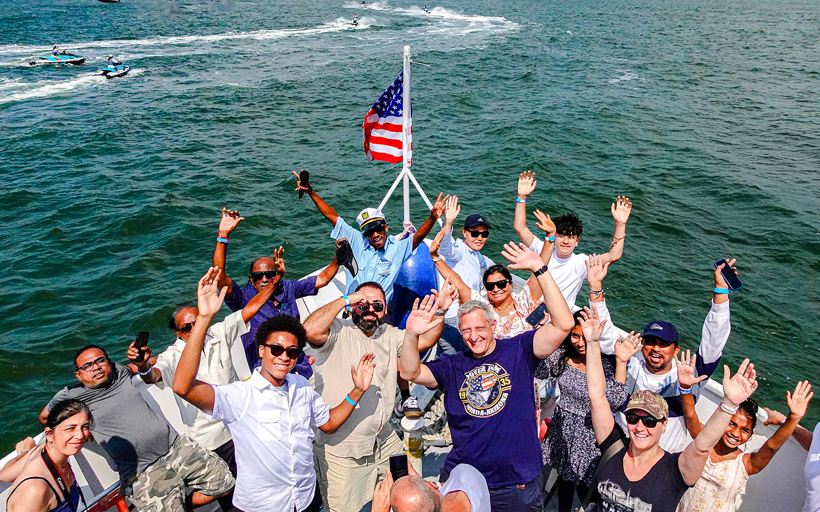 Guests enjoying the Statue of Liberty and NYC landmarks cruise, waving on a boat.