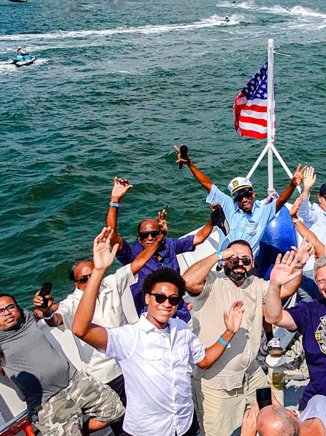 Guests enjoying the Statue of Liberty and NYC landmarks cruise, waving on a boat.