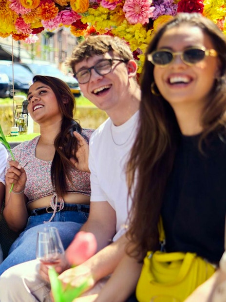 Group enjoying Amsterdam canal cruise on a flower-adorned boat.