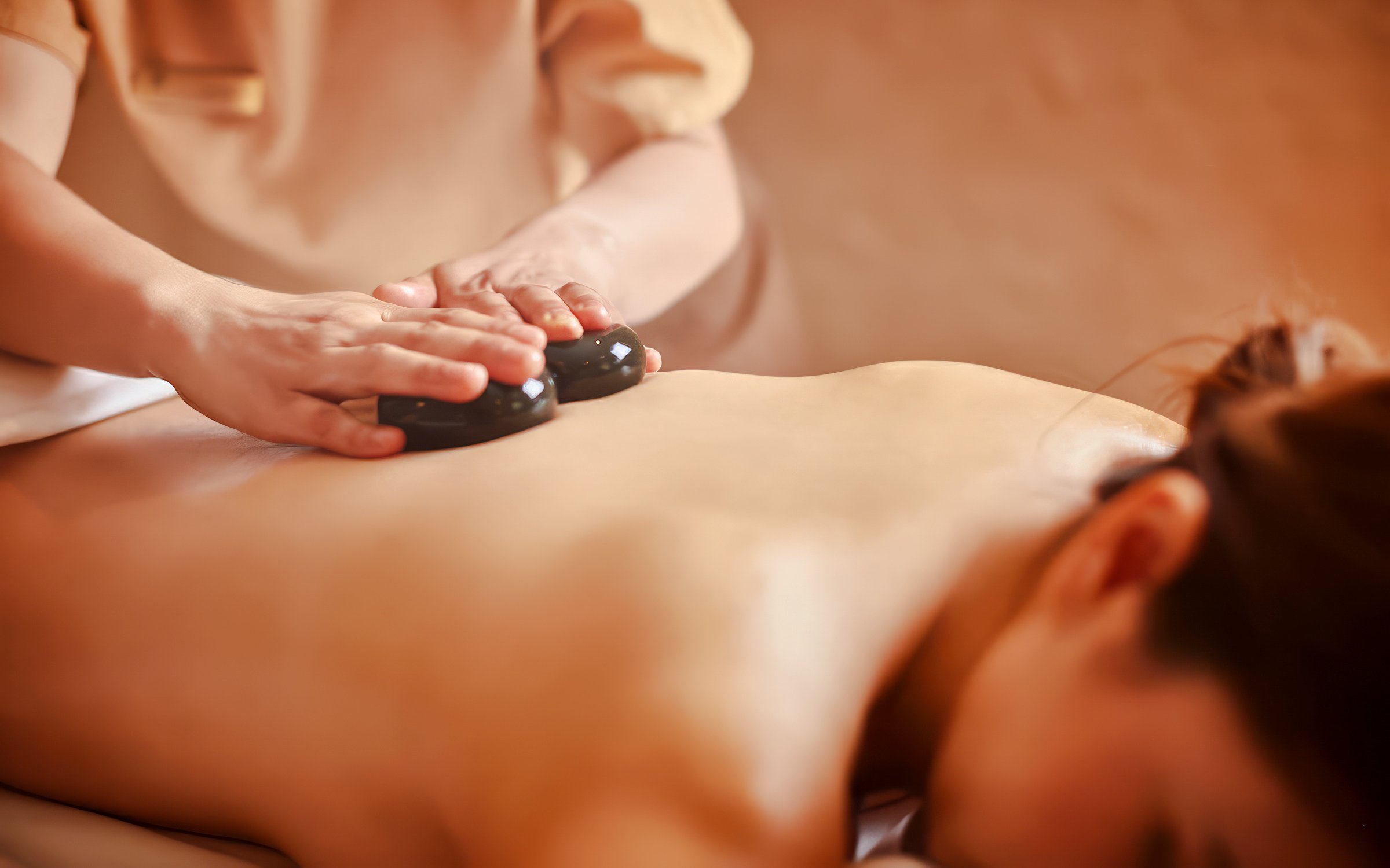 Tourist receiving hot stone massage with organic aromatherapy oils.