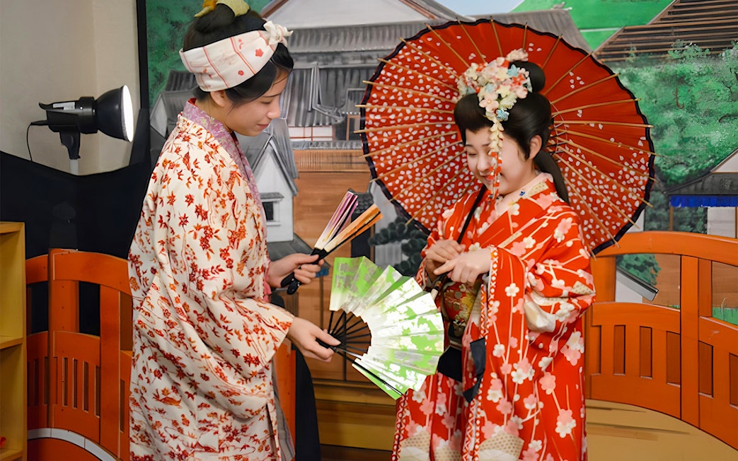 Women in traditional kimonos with fans at Noboribetsu Date Jidaimura, Japan.