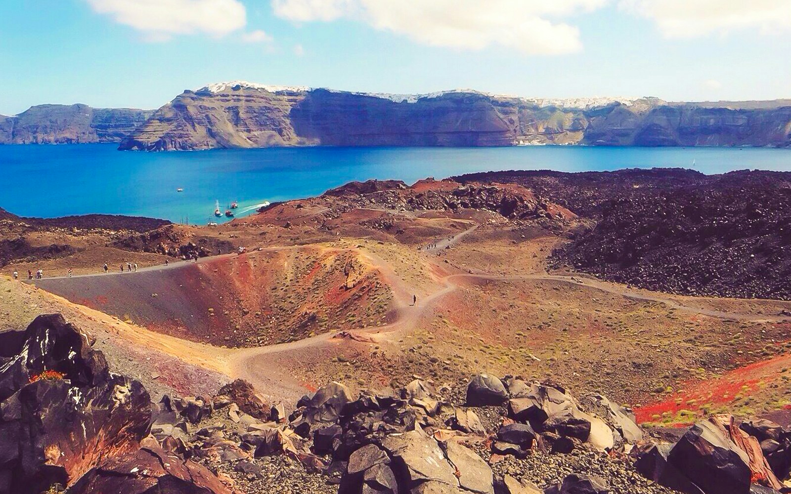 Santorini volcanic islands boat tour with view of caldera, hot springs, and Thirassia in the background.