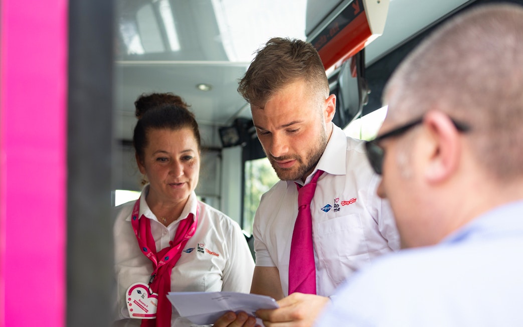 Tour guides assisting a passenger on the I Love Rome Hop-On Hop-Off bus tour.