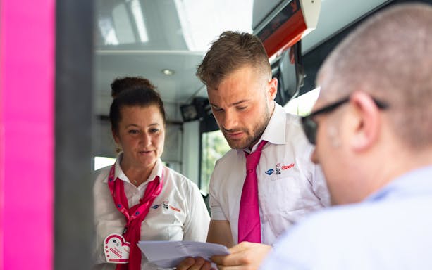 Tour guides assisting a passenger on the I Love Rome Hop-On Hop-Off bus tour.