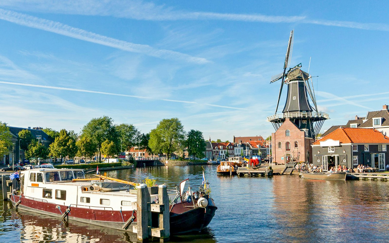 Canal cruise on the Spaarne River with views of a traditional windmill in Haarlem, Netherlands.
