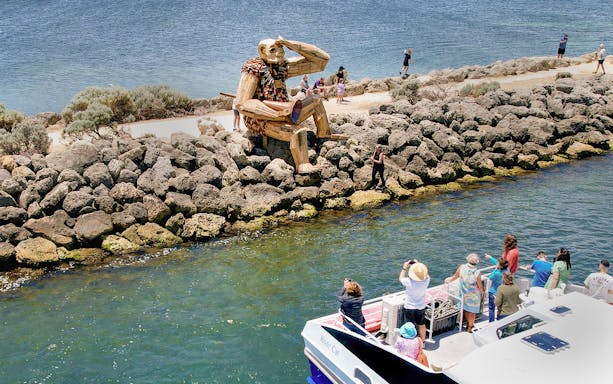 Tourists on boat viewing giant sculpture on Giant & Dolphin Sightseeing Cruise.