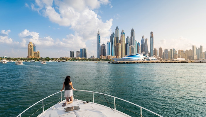 Yacht cruising in Dubai Marina with city skyline in the background.