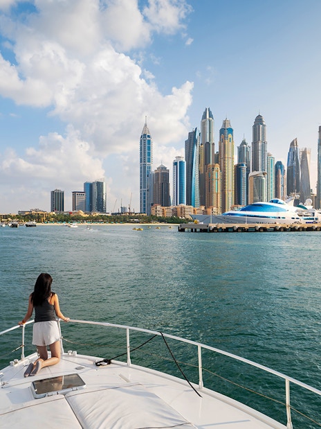 Yacht cruising in Dubai Marina with city skyline in the background.