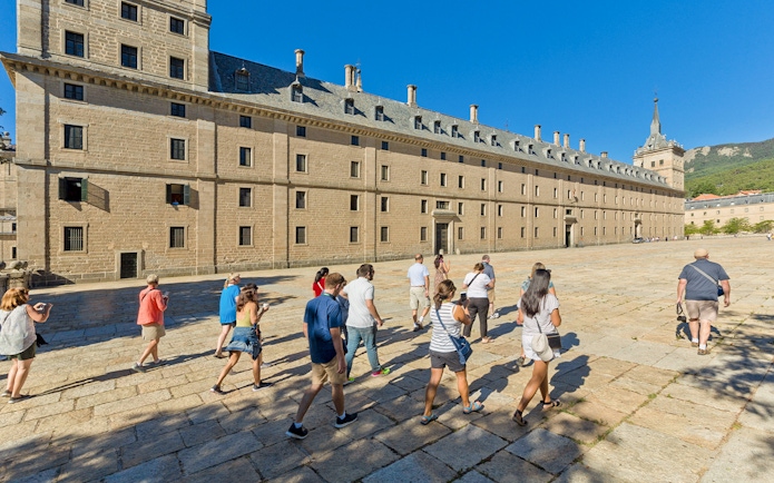 Group of tourists walking towards San Lorenzo de El Escorial in Spain.