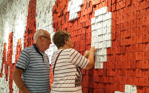 Tourists interacting with a wall of notes at the European Solidarity Center.