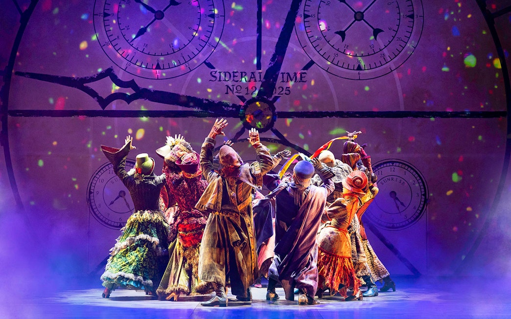 Performers in colorful costumes on stage during a scene from the musical Wicked.