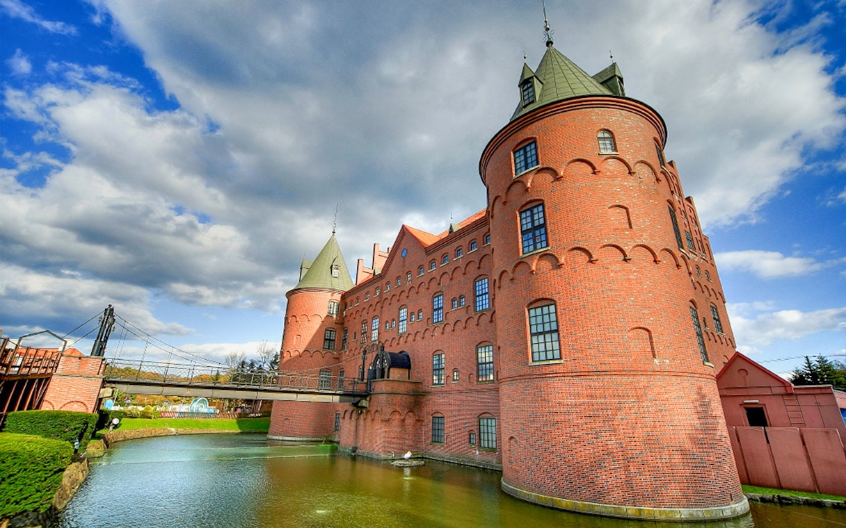 Noboribetsu Marine Park NIXE castle with moat and bridge under blue sky.
