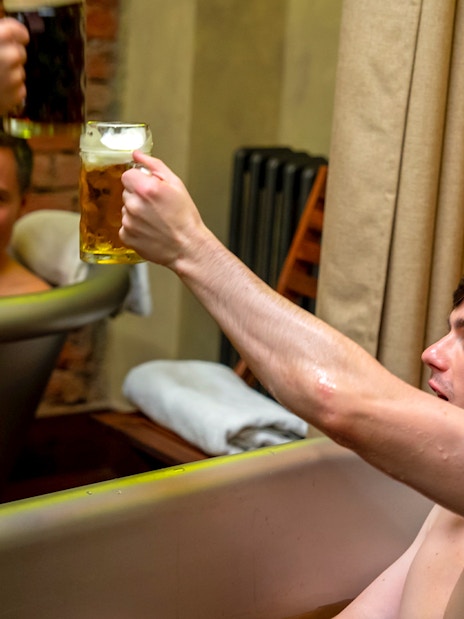 Men enjoying beer in a spa bath, raising mugs in a toast.