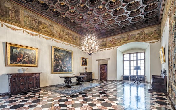 Wawel Castle interior with ornate ceiling, paintings, and chandelier in Krakow.