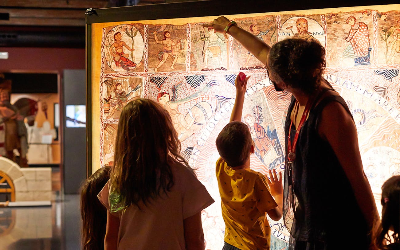 Visitors examining a tapestry at the History Museum of Catalonia.