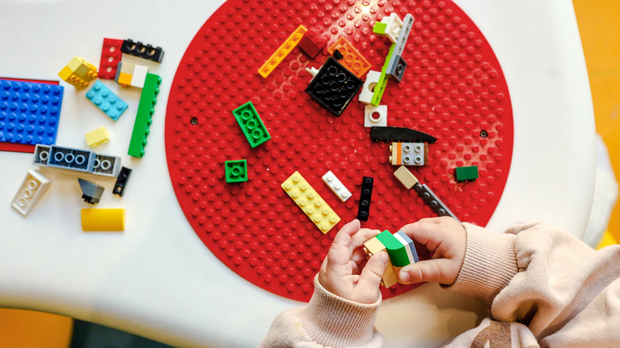 Child assembling colorful blocks on a red circular baseplate.