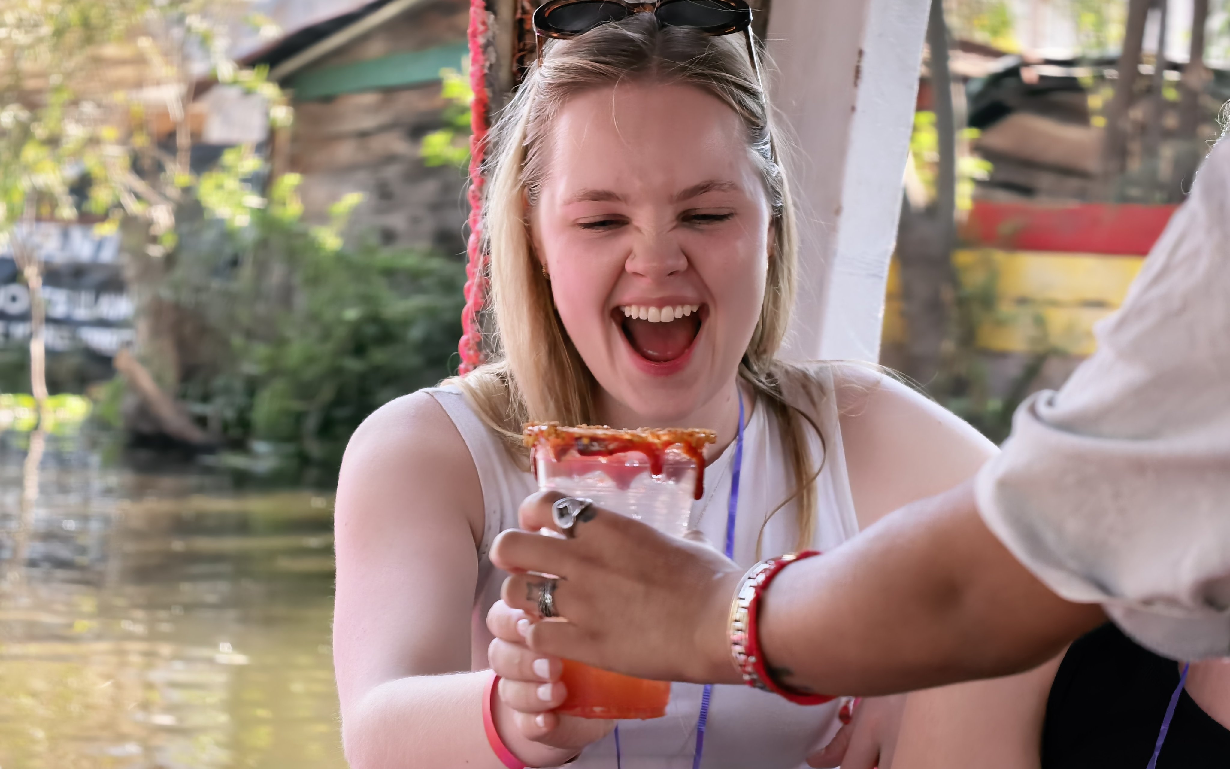 Woman enjoying a drink on an Aztec canal tour with festive atmosphere.