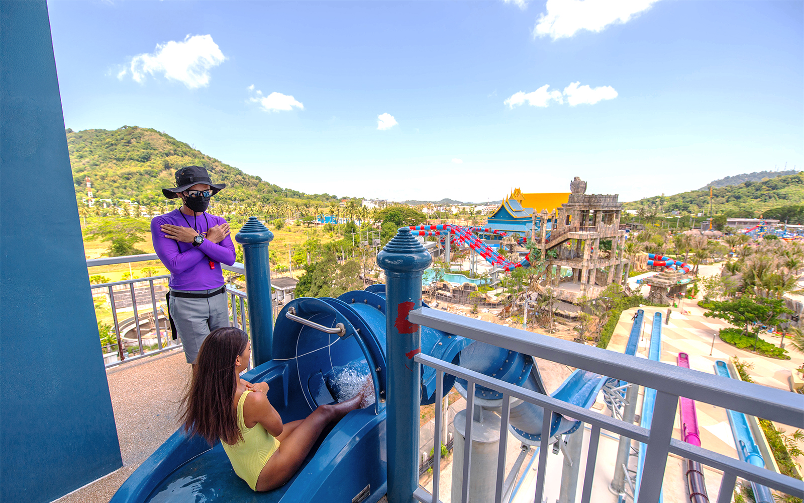 Person preparing to slide at a water park in Phuket, Thailand, with scenic view.
