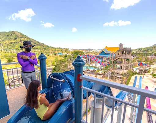 Person preparing to slide at a water park in Phuket, Thailand, with scenic view.