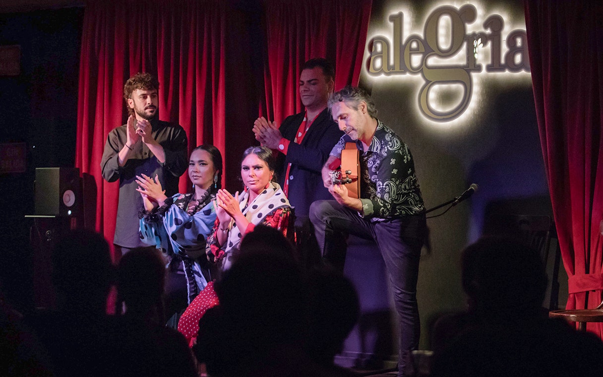 Flamenco performers on stage at Alegría, with guitarist and dancers clapping.