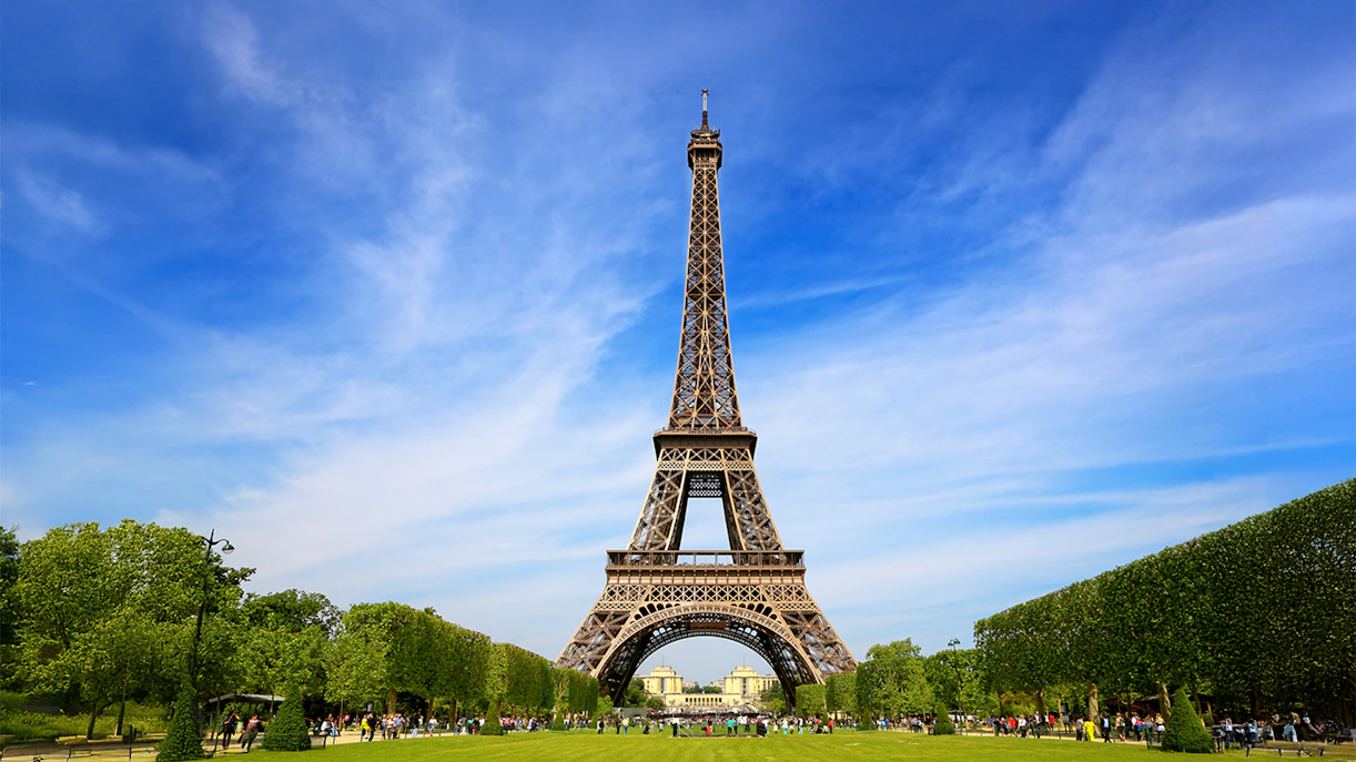 Eiffel Tower with tourists gathered for guided climb to second floor via stairs.
