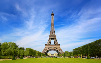Eiffel Tower with tourists gathered for guided climb to second floor via stairs.