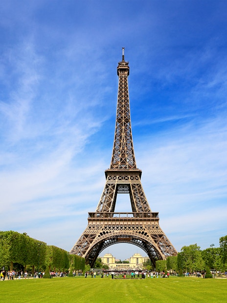 Eiffel Tower with tourists gathered for guided climb to second floor via stairs.