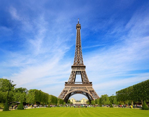 Eiffel Tower with tourists gathered for guided climb to second floor via stairs.