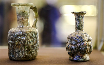 Ancient glass bottles displayed in Amman museum during city sightseeing tour.