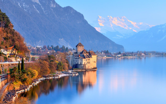 Chillon Castle on Lake Geneva with snow-capped mountains in the background.