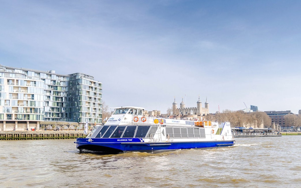Cruise boat on Thames River with Tower of London in the background, London.