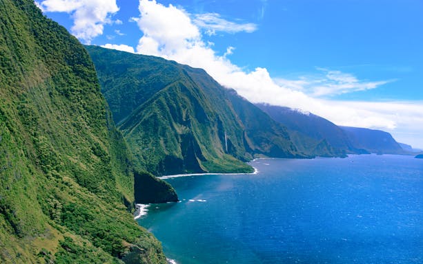 Aerial view of lush cliffs and ocean on a helicopter tour over Maui and Molokai, Hawaii.