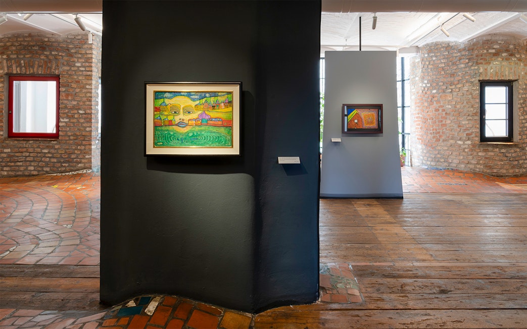 KUNST HAUS WIEN exhibit featuring colorful Hundertwasser paintings on brick walls.