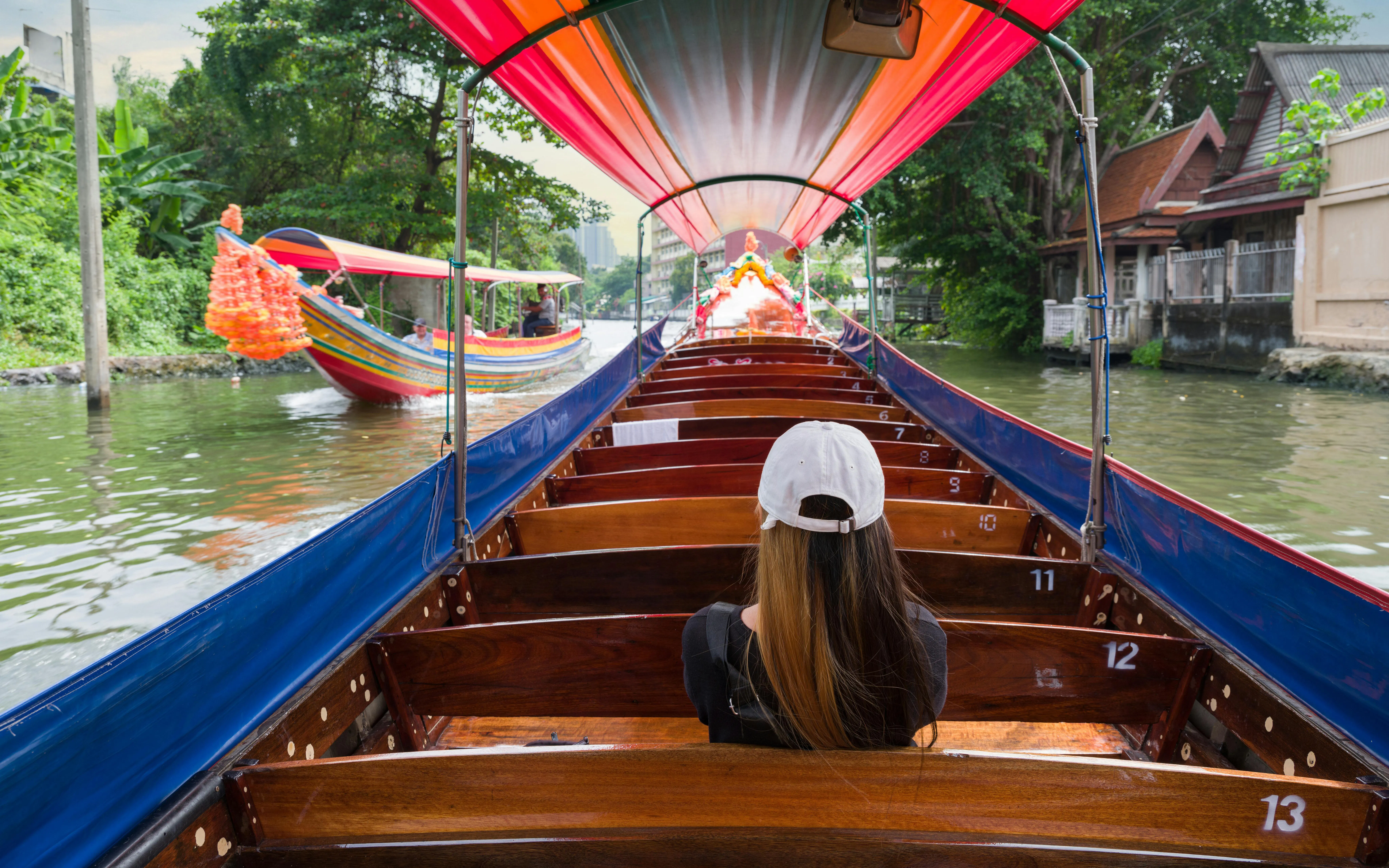 Tourist on a traditional boat cruising Chao Phraya River canal, Bangkok.