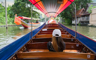 Tourist on a traditional boat cruising Chao Phraya River canal, Bangkok.