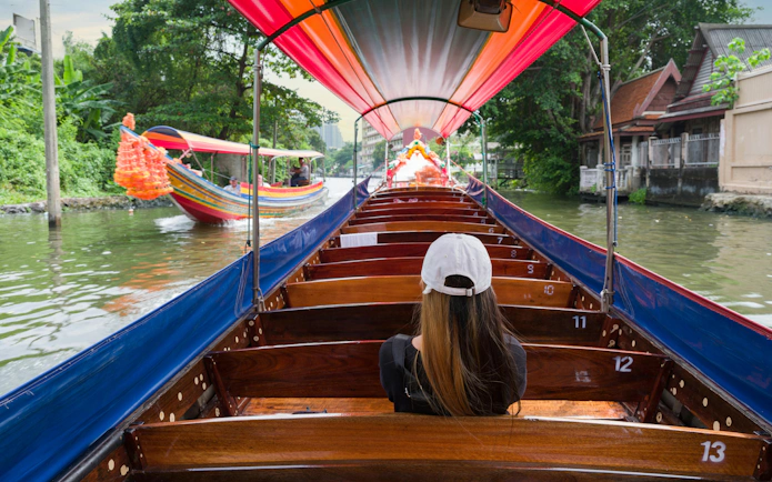 Tourist on a traditional boat cruising Chao Phraya River canal, Bangkok.