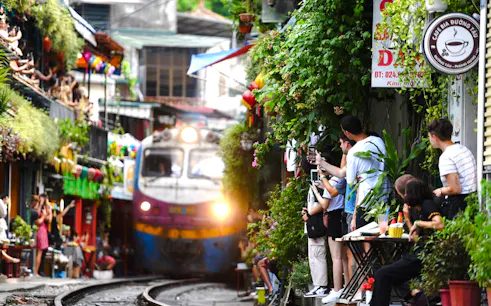 Train passing through Hanoi's Train Street with tourists capturing photos, Hanoi Photo Tour on Vespa.